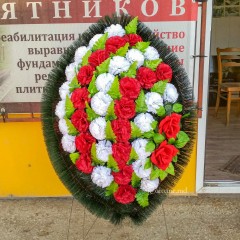 Оригинальный траурный венок 80см из искусственных цветов. Цветы: красные гвоздики, белые гвоздики, красные розы. Зелень: папоротник, роза. Каркас: хвоя.