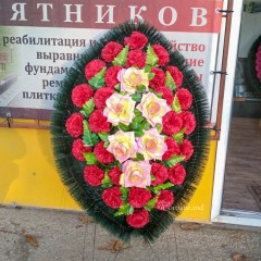 Оригинальный траурный венок 80см из искусственных цветов. Цветы: красные гвоздики, розово- жёлтые розы. Зелень: папоротник, роза. Каркас: хвоя.