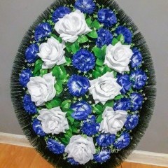 Оригинальный траурный венок 80см из искусственных цветов. Цветы: сине-белые гвоздики, белые розы. Зелень: роза, белые полевые цветы. Каркас: хвоя.